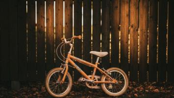 Børnecykel ved skandinavisk havegærde i eftermiddagssol