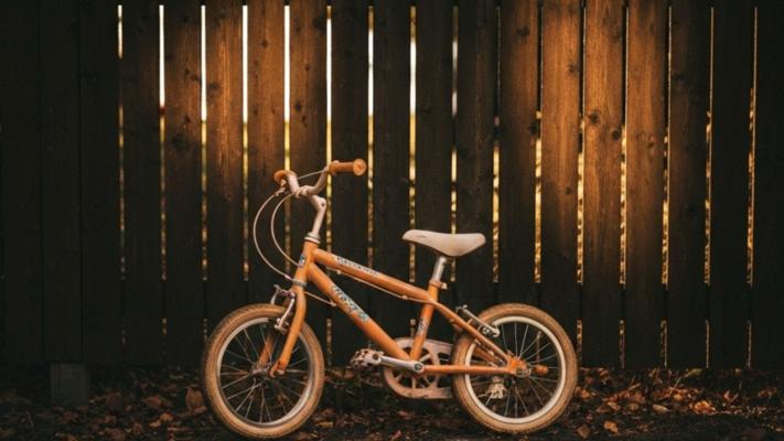 Børnecykel ved skandinavisk havegærde i eftermiddagssol